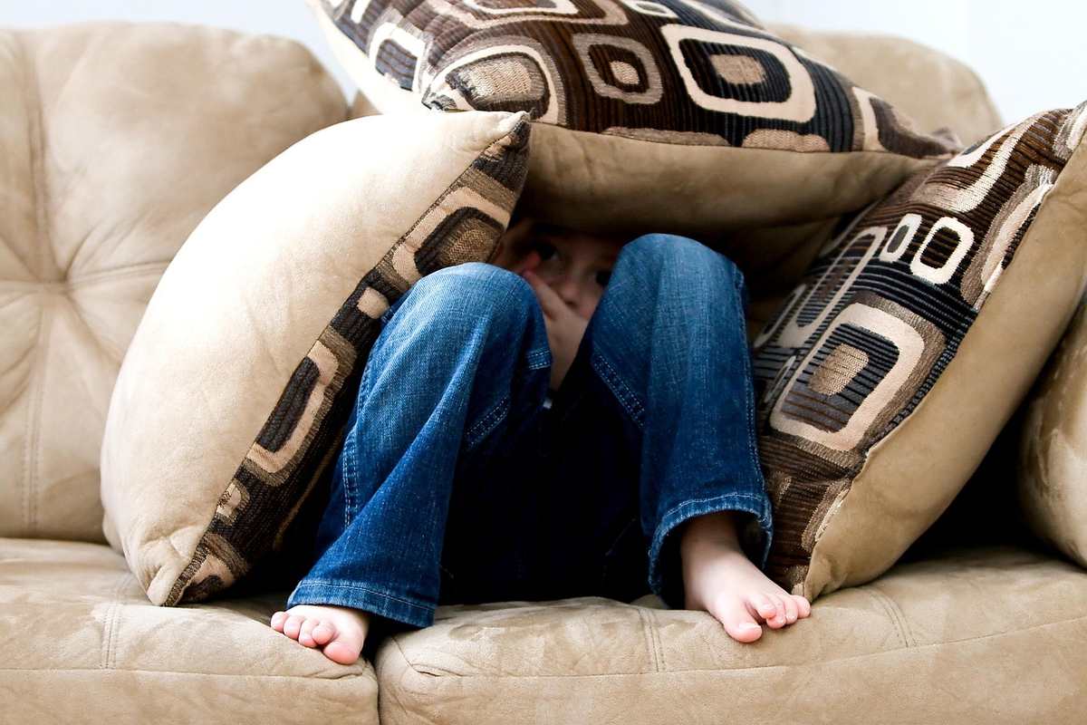 Enfant caché sous des coussins sur un canapé Enfant caché sous des coussins sur un canapé