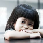 Petite fille brune aux cheveux droits et au visage rond, les coud