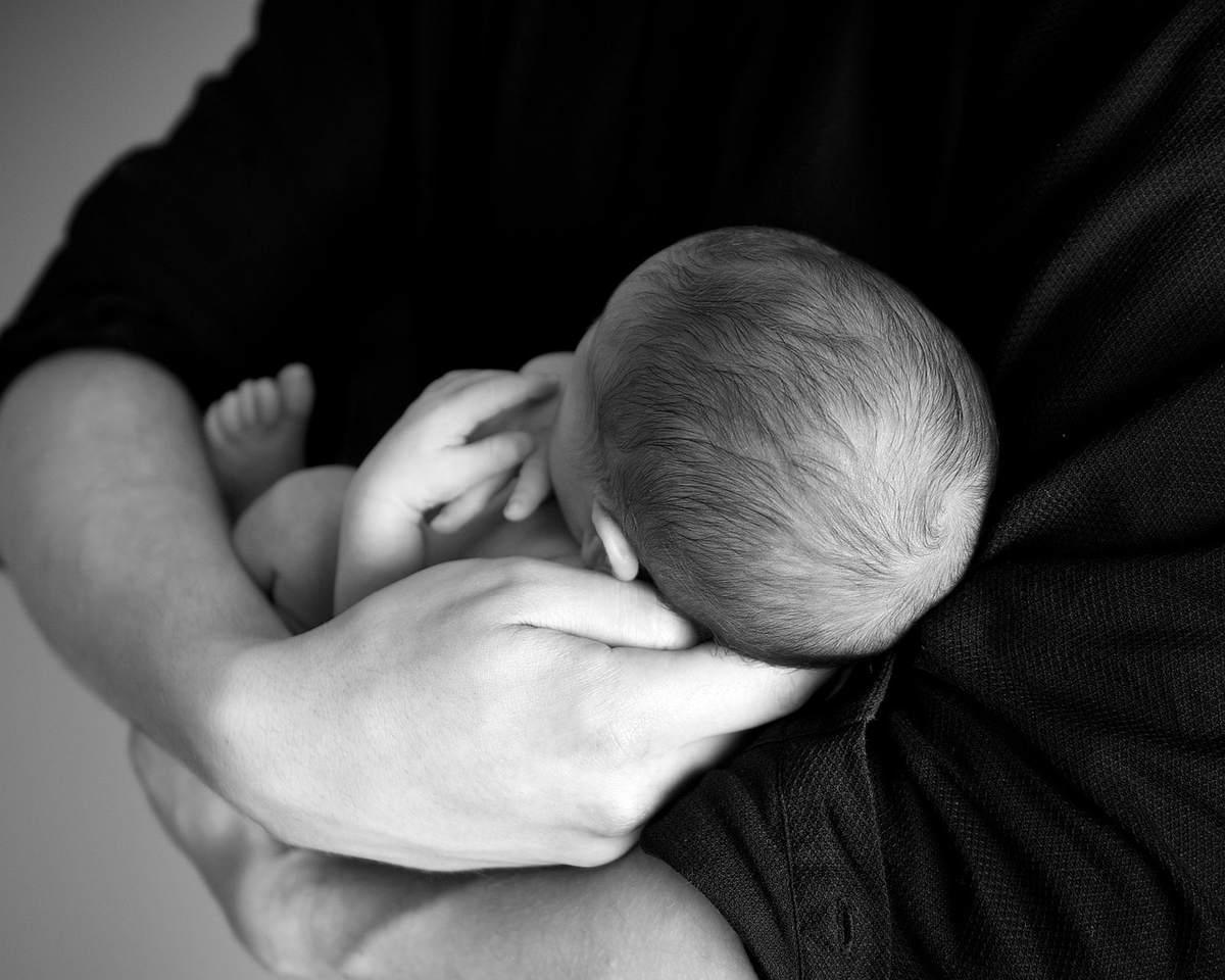 Un adulte serre tendrement un nourrisson nouveau-né contre son corps Un adulte serre tendrement un nourrisson nouveau-né contre son corps