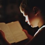 Enfant absorbé dans la lecture d'un livre, éclairé par une lumière dorée