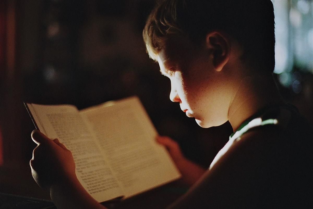 Enfant absorbé dans la lecture d'un livre, éclairé par une lumière dorée