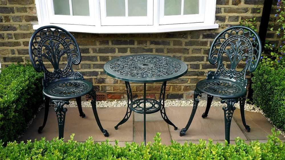 Deux chaises en fer forgé, petite table ronde, mur en brique, jardin