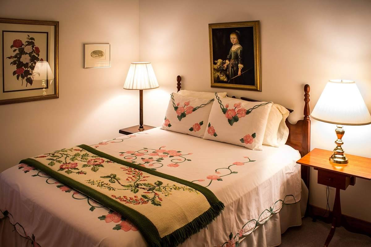 Chambre d'hôte décorée avec lits douillets, lampes de chevet allumées, tableaux muraux